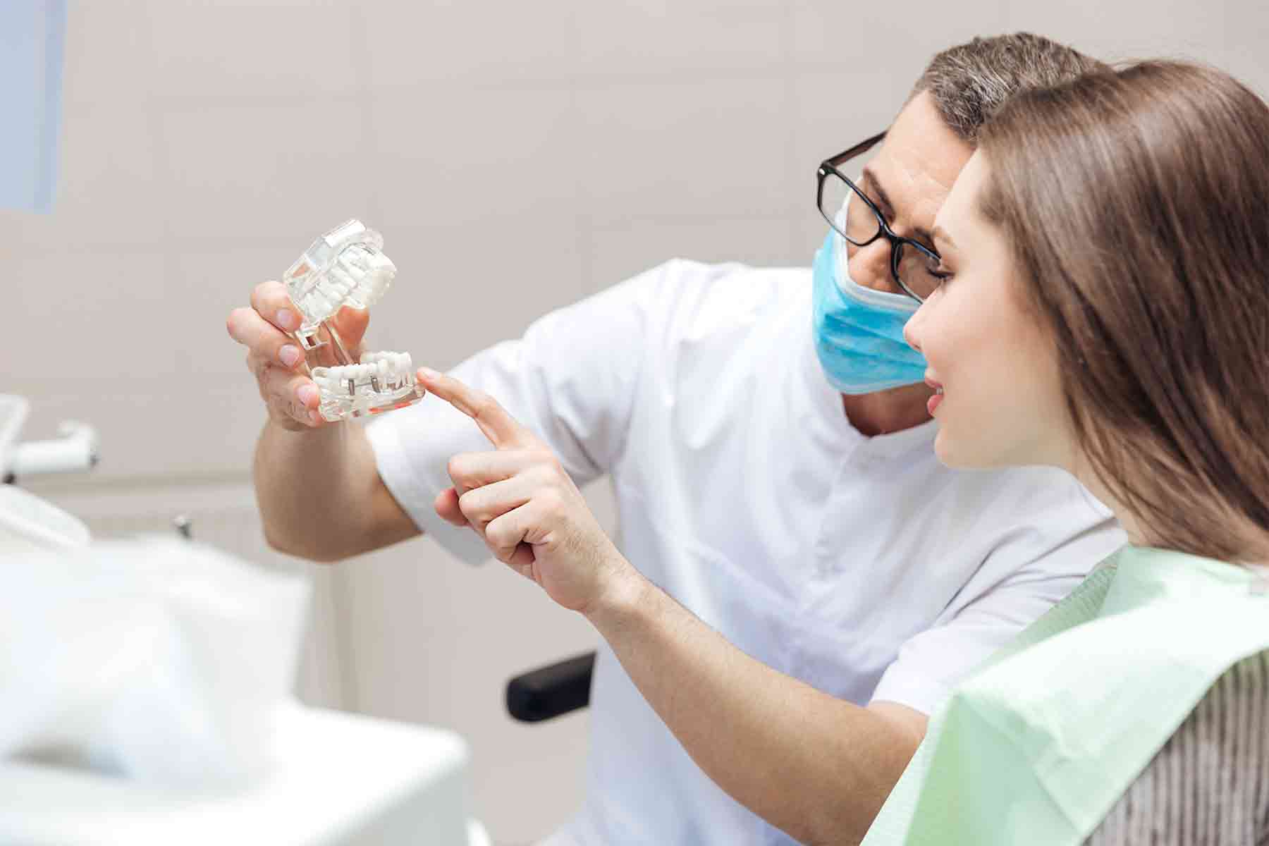 Dentista explicando a una paciente la colocación de implante y corona dental